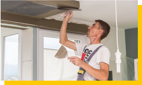 plasterer working around ceiling aircon unit