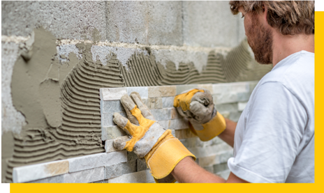 tiler working on breezeblock wall
