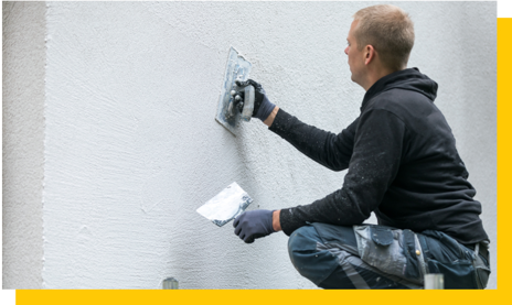 crouching pasterer smoothing outside wall